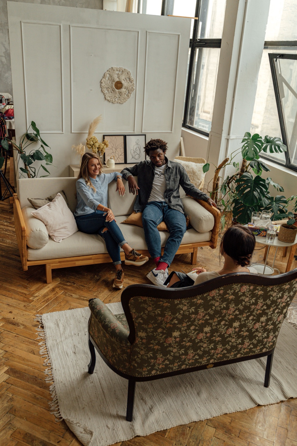 A couple sits together on a sofa talking with their therapist