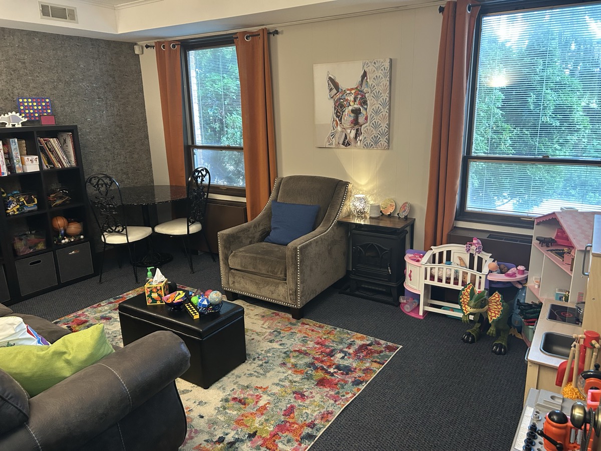 Pivotal Counseling Center play therapy room with toys, a play kitchen, a dollhouse and cozy seating
