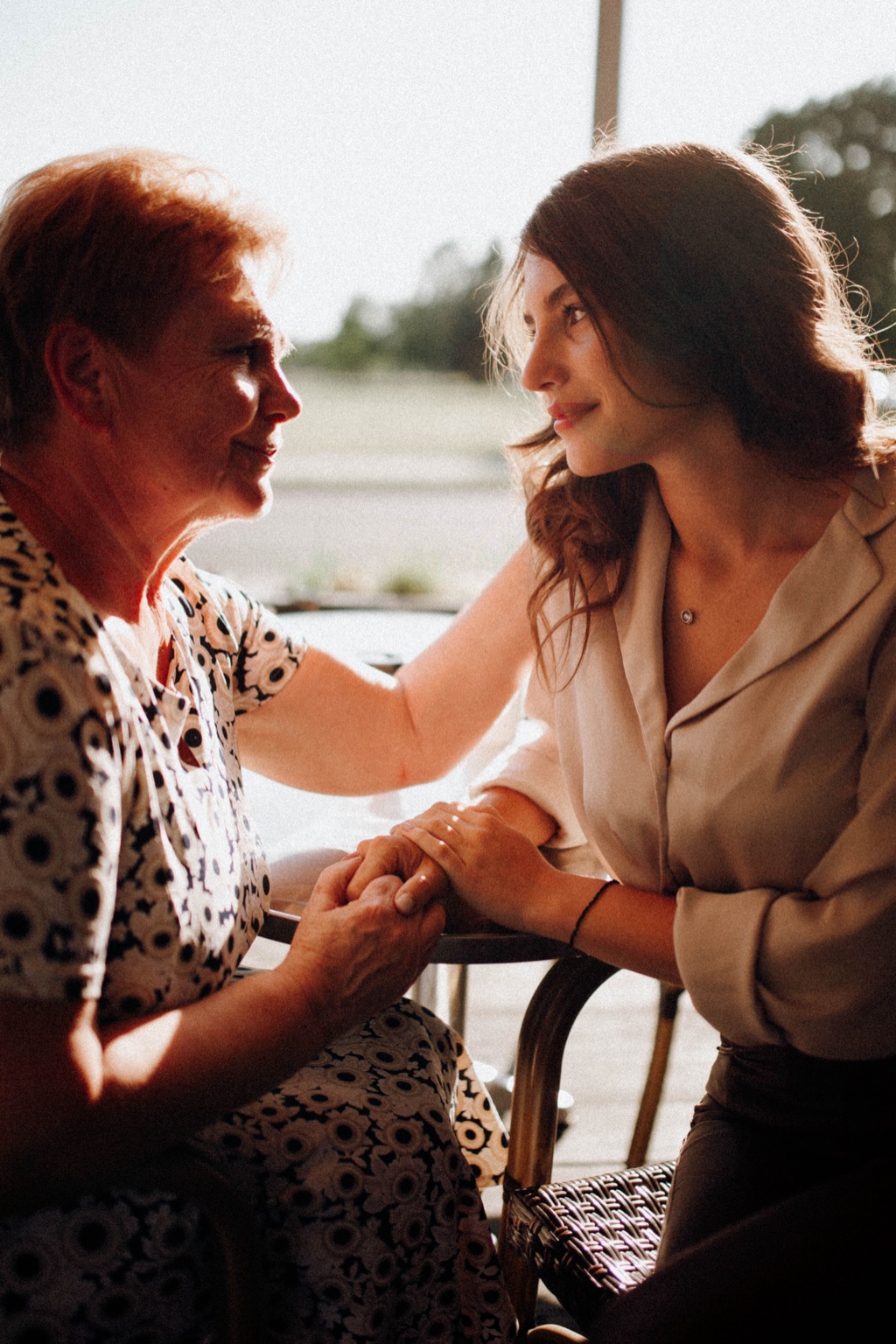An older woman and a younger woman hold hands and share a quiet moment
